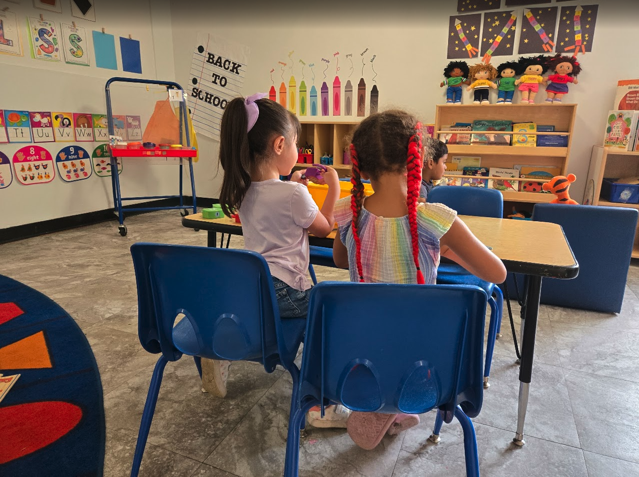 Two children working at desks in a colorful back-to-school classroom